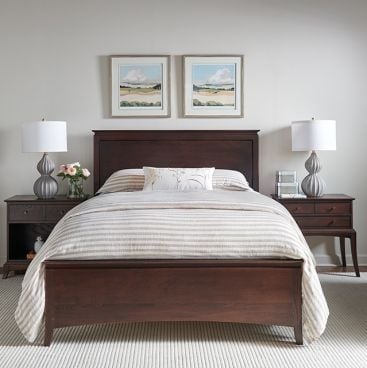 A solid wood bed in a bedroom with nightstands and two lamps.