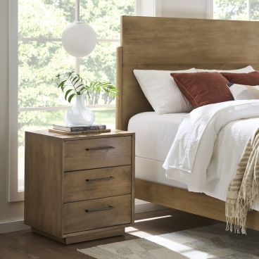 Wooden three-drawer nightstand paired with a sleek wooden bed, showcasing clean lines and functional design in a contemporary bedroom setting.
