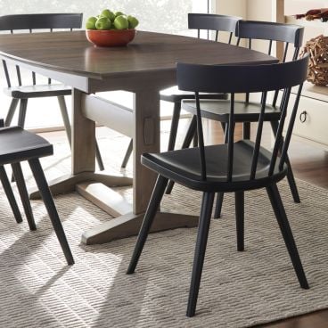 Sleek black wooden dining chairs arranged around a sturdy wooden trestle table, adding modern sophistication to the dining area.