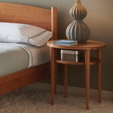 real wood circle nightstand next to a matching wood bed frame