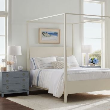 A sleek, handcrafted solid wood canopy bed with a minimalist frame and a clean-lined headboard, designed for modern elegance and durability.