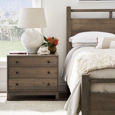 Three-drawer nightstand featuring natural wood grain and sleek black hardware.