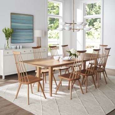 Dining room with natural wood furniture, including a spacious table and matching spindle-back chairs, paired with a white buffet.