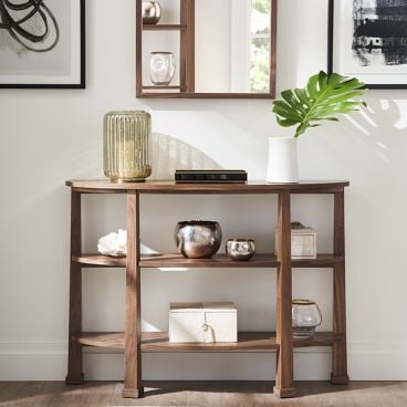 Elegant demilune console table made from solid walnut, featuring display shelves with various decor.