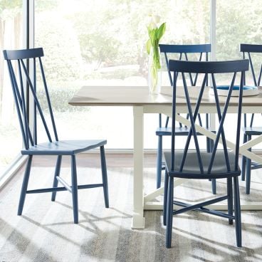 Set of solid wood dining chairs with an intersecting spindle-back design, painted in a deep blue finish, paired with a handcrafted wood dining table.