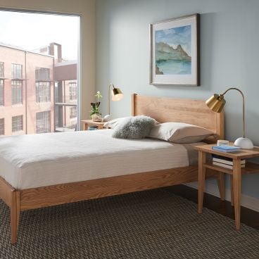 A city apartment bedroom featuring a real wood platform bed with matching nightstands.