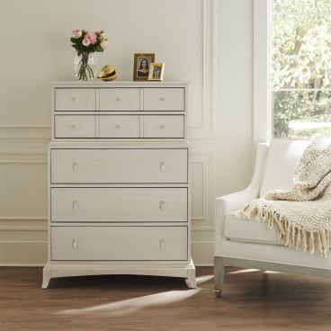 Elegant highboy dresser with nine drawers made from real wood painted white in a bright, airy bedroom