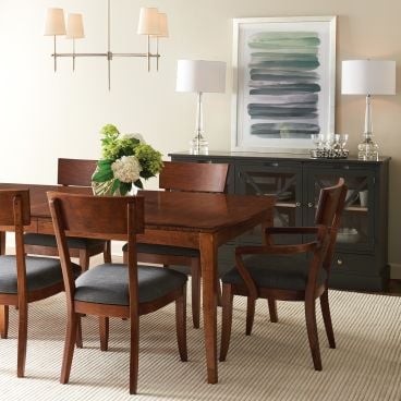 Solid cherry wood dining table with matching chairs, featuring a warm finish and upholstered seats, set in an elegant dining room