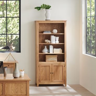 Tall wooden bookshelf featuring multiple open shelves and a cabinet base for additional storage.