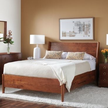 Elegant bedroom featuring a solid cherry wood bed and dresser set, highlighted by crisp white decor and a warm, inviting atmosphere.