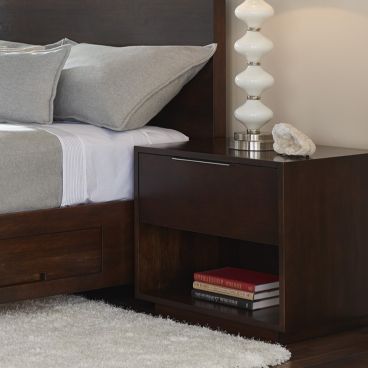 Elegant bedroom set in dark wood, including a bed with storage and a matching nightstand, complemented by soft lighting and minimalist design.