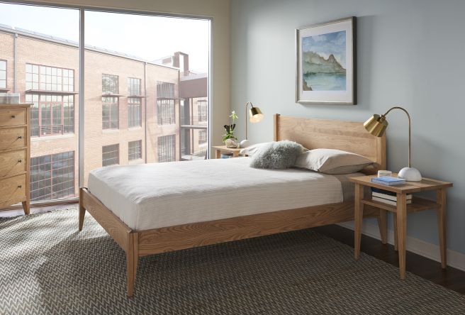 Bright and airy bedroom with large industrial-style windows, showcasing a sustainable Appalachian hardwood bed and nightstand