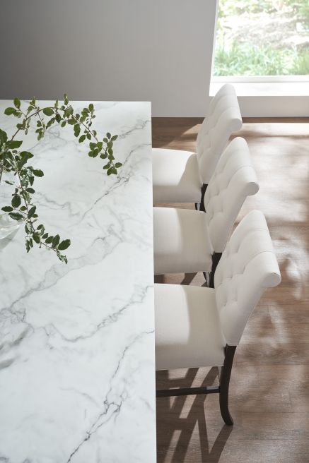 Top view of plush, white upholstered counter chairs paired with a sleek marble dining kitchen island.