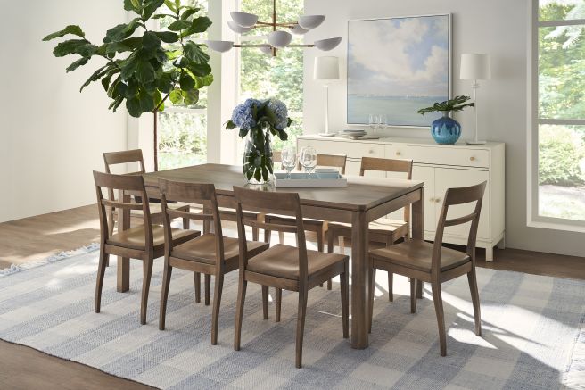 Dining room featuring a sleek wooden dining table with six matching wooden chairs, set against a backdrop of neutral tones and soft sunlight.