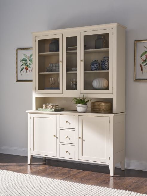 Solid wood buffet with upper hutch and storage drawers, shown in a bright dining room with dark wood floors.