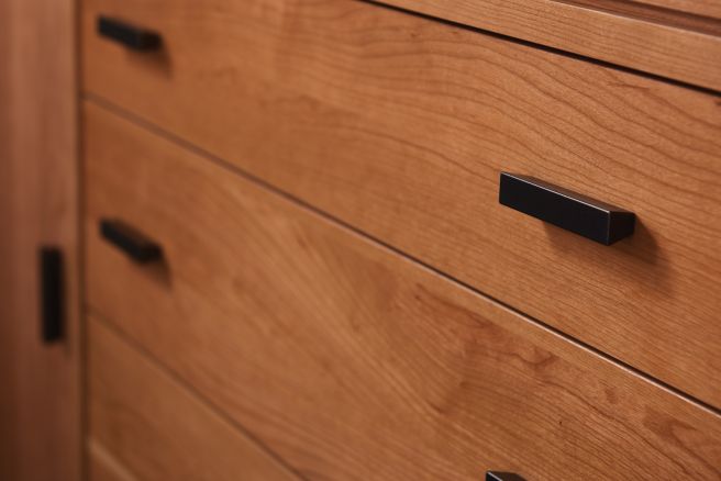 Close-up of a wooden credenza with modern black handles.