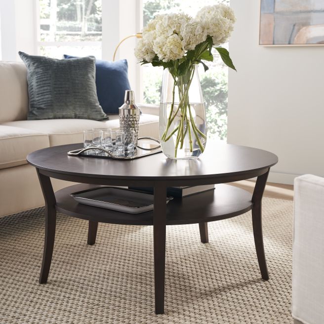 Elegant coffee table made from dark-stained wood, highlighting its curved legs and smooth tabletop, complemented by modern decor.