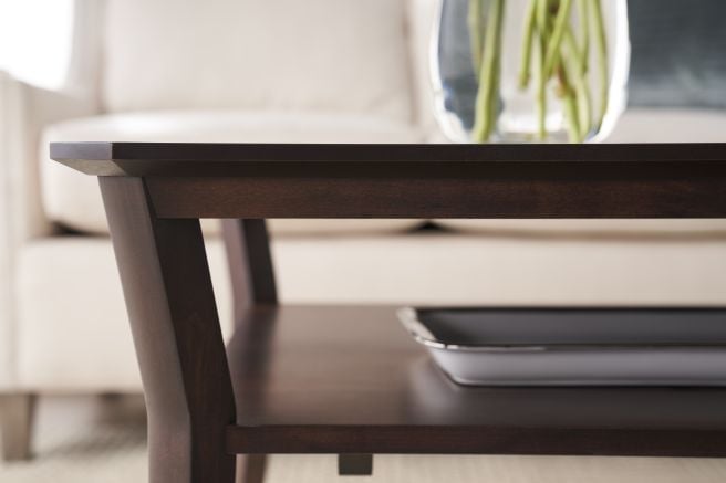 Close-up of a finely crafted coffee table featuring tapered legs and a sleek wooden finish, with a tray elegantly placed on the lower shelf.