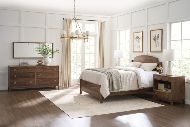 Walnut wood bedroom set with a six-drawer dresser, matching nightstand, and bed frame, styled in a light-filled room.