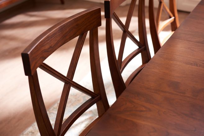 Handcrafted hardwood dining chair featuring a double X-back design and a sculpted wood seat, finished in rich brown stain.