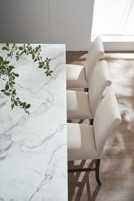 Row of upholstered dining chairs positioned next to a marble-top dining table, showcasing refined craftsmanship and modern dining elegance.