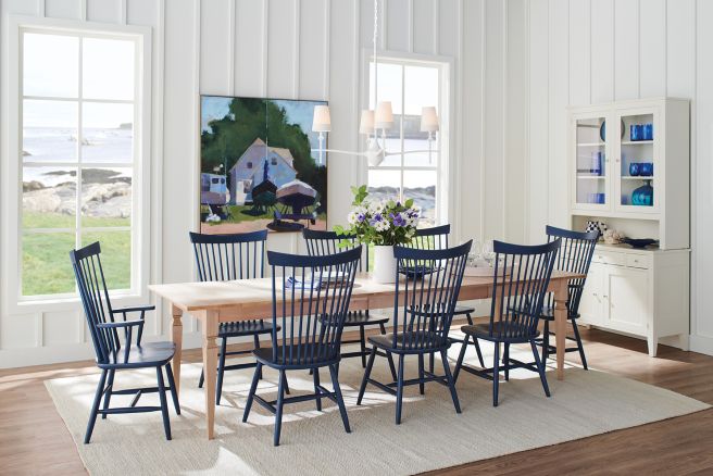 Light wood farmhouse-style dining table paired with elegant navy spindle chairs, creating a fresh and inviting dining space