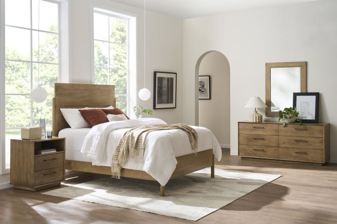 A bedroom showcasing the Josie bed with a sturdy wood frame and cylindrical legs, complemented by the Amelia dresser and nightstand with modern drawer pulls.