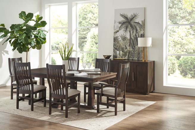 Warm and inviting dining space showcasing a dark wooden table and chairs, complemented by a matching server and lush indoor plant.