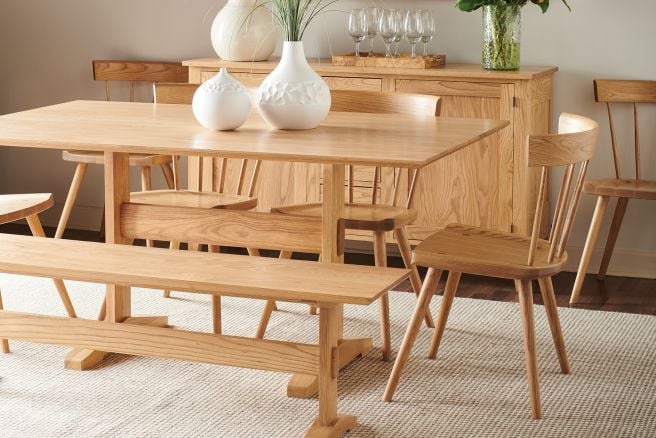 A solid wood dining set featuring a trestle table, matching solid wood chairs, and bench, showcasing a natural wood finish and minimalist design.