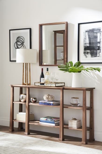 Handcrafted wooden console table, showcasing elegant decor pieces and a modern mirror in a living room setting.
