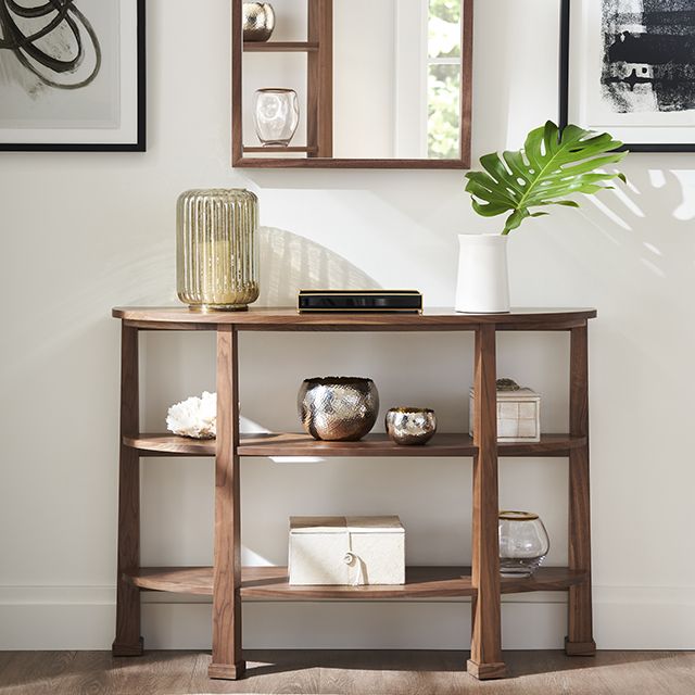 Elegant demilune console table made from solid walnut, featuring display shelves with various decor.