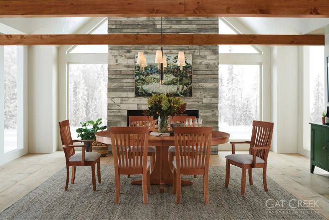 Rustic dining room featuring a handcrafted round wooden table with matching chairs, set against a snowy mountain view
