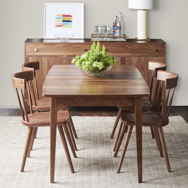 Elegant walnut wooden dining set featuring a rectangular table and matching chairs, complemented by a modern sideboard and greenery centerpiece.