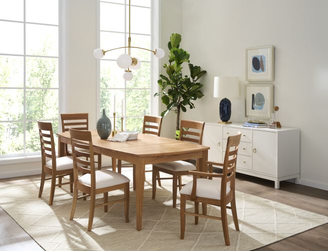 A modern dining room featuring a rectangular wooden table surrounded by ladder-back chairs with upholstered seats.