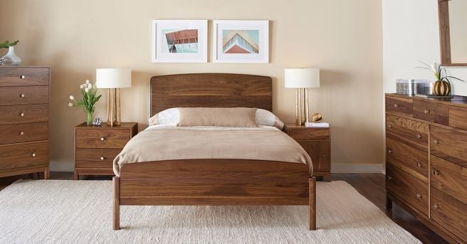 Warm and inviting bedroom with a solid wood bed and coordinating furniture, styled with neutral bedding and soft lighting.
