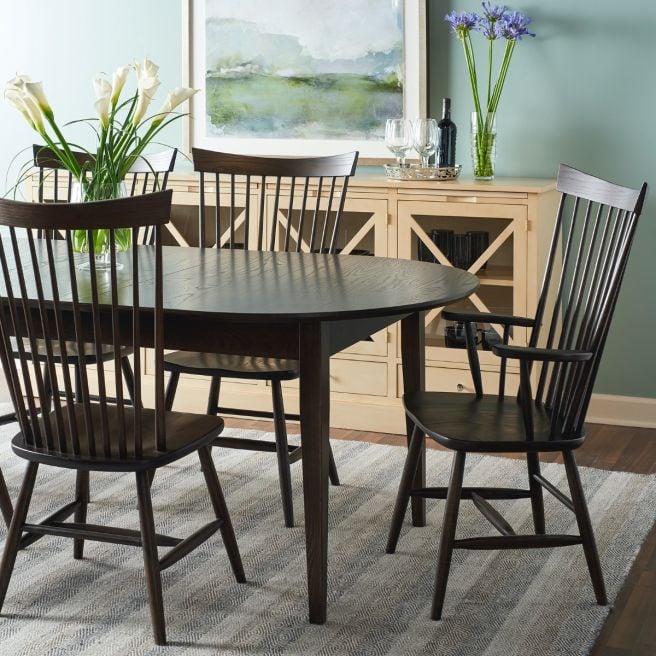 Elegant wooden dining chairs surrounding a round table with a backdrop of a light wooden buffet.
