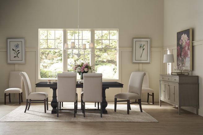 Sophisticated dining area showcasing a dark wood dining table with beige upholstered chairs, paired with a light wood sideboard and framed floral prints