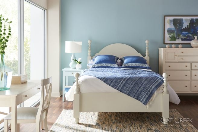 A handcrafted solid wood bed with turned posts and an arched headboard, accompanied by a matching dresser and nightstand in a classic design.