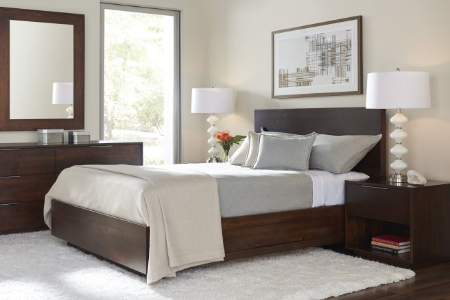 Modern bedroom with dark wood bed, matching nightstand and dresser, featuring clean lines and a large mirror above the dresser.