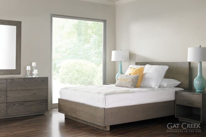 Modern bedroom featuring a sleek solid wood platform bed in a flannel gray finish, complemented by matching nightstands and a dresser, with soft lighting and natural accents.
