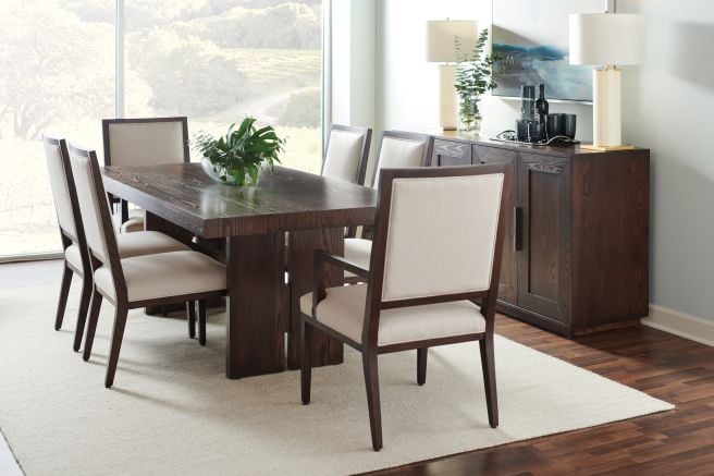 Modern dining room featuring a solid wood table with a dark finish, paired with upholstered chairs and a matching sideboard