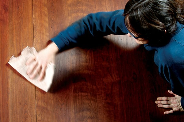 Photo of woman wiping wood surface